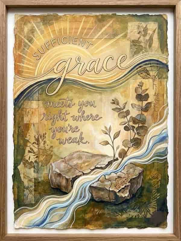 Framed mixed-media watercolor artwork featuring the calligraphic quote "Sufficient grace meets you right where you're weak" set against warm earth tones, a glowing sunburst, a stream flowing through a cracked rock, and growing eucalyptus branches.